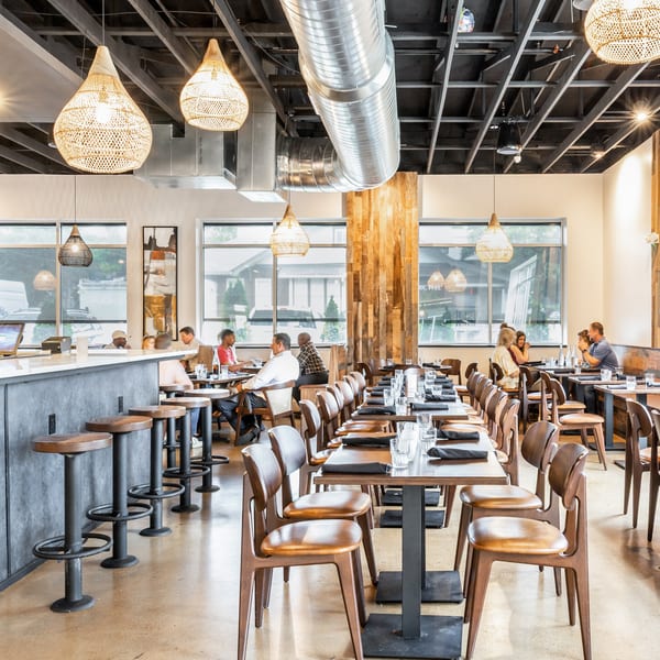 Modern restaurant interior with a bar, dining tables, and patrons enjoying meals.